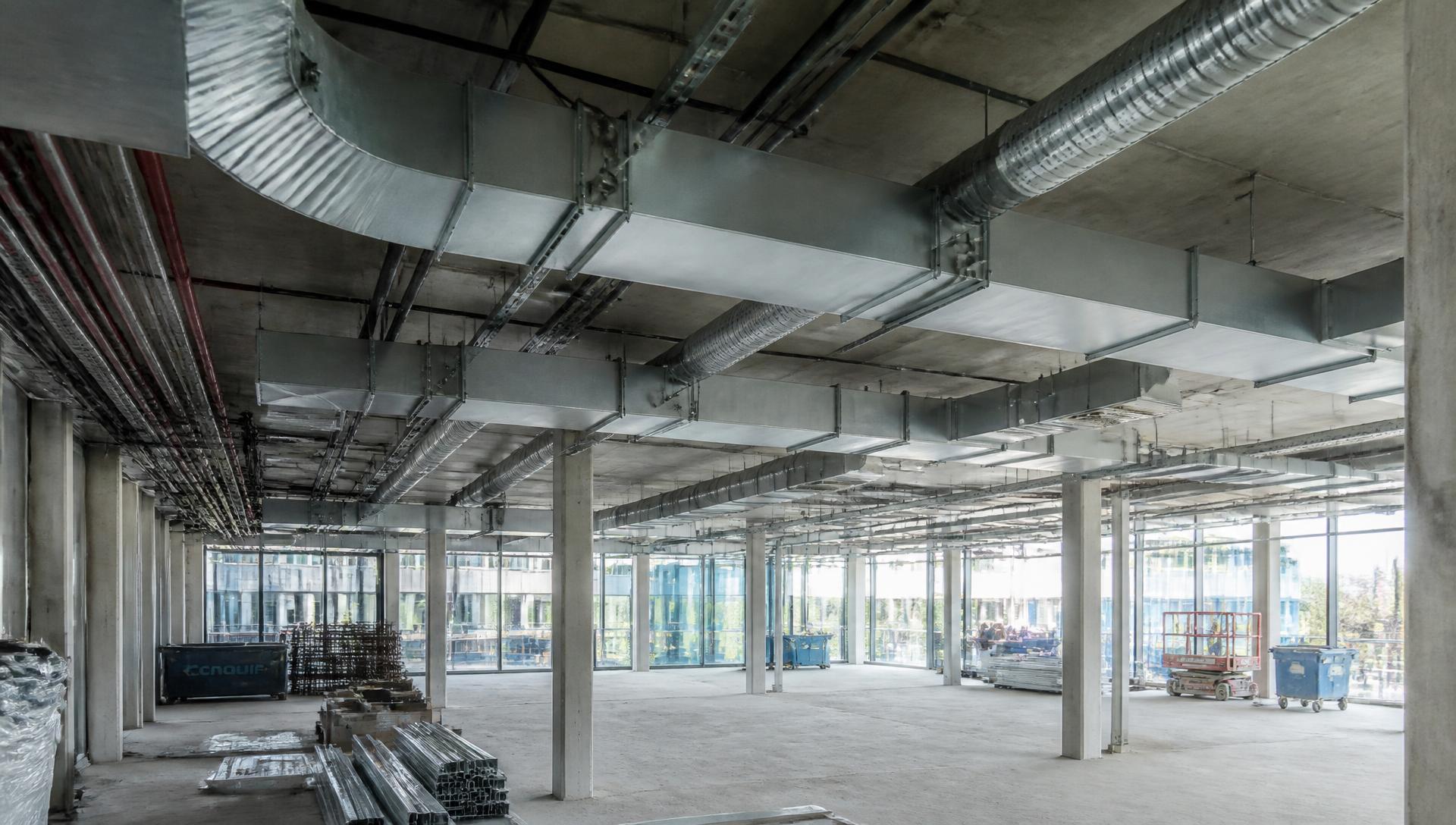 Exposed galvanised rectangular and spiral ductwork installed beneath a concrete soffit on a London commercial project